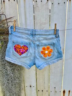 This listing is a pair of Celebrity Pink shorts transformed into a stunning display of upcycled fashion artistry. These shorts are adorned with hand-sewn appliqué designs featuring vintage Hawaiian fabric, including a delicate heart and vibrant flower. Each appliqué brings a burst of color and retro charm to the denim, creating a unique blend of tropical nostalgia and contemporary style. These upcycled Celebrity Pink shorts not only showcase meticulous craftsmanship but also promote sustainabili Handmade Fitted Summer Bottoms, Handmade Fitted Bottoms For Summer, Upcycled Bottoms For Summer, Handmade Short Bottoms For Summer, Handmade Short Summer Bottoms, Handmade Summer Shorts, Fitted Patchwork Shorts For Summer, Upcycled Bohemian Bottoms For Spring, Spring Festival Cotton Jean Shorts