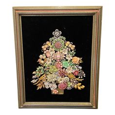 a small framed christmas tree with flowers on it's side and other decorations around the base