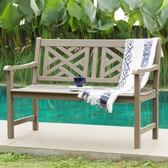 a wooden bench sitting next to a pool with a towel on it's back