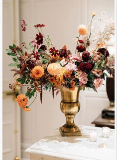 a vase filled with lots of flowers sitting on top of a table next to a candle