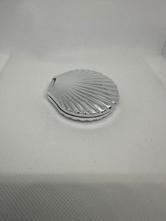 a silver object sitting on top of a white cloth covered bedding area with no sheets