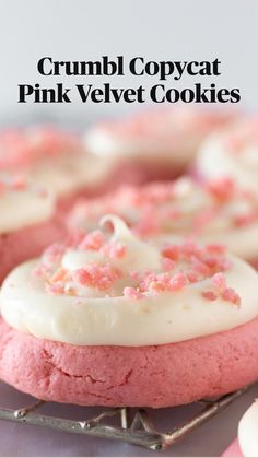 pink velvet cookies with white frosting and sprinkles on top, sitting on a cooling rack