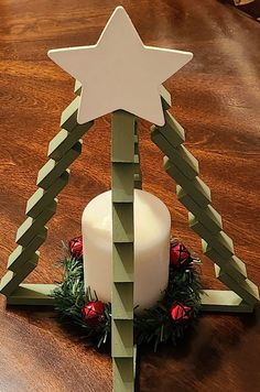 a christmas tree candle holder made out of wood sticks with a white star on top