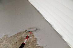 a person is using a paint roller to fix a floor that has been stained white