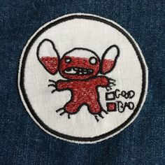 an embroidered patch on the back of a jean jacket with a red and white design