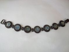 Stunning vintage bracelet by Modernist designer Luli Hammerztein. This artist uses only authentic artifacts in her creations. This bracelet features a stunning Modernist design, beautiful round links of sterling silver and blue with speckles Roman Glass.  Signed on back of each link. Measures 7.5 inches long approx, 3/4 inches wide. Beautiful condition, secure hook clasp. Truly a Beautiful creation! Antique Oxidized Finish Bracelets, Antique Bracelet With Oxidized Finish, Antique Round Bracelet With Oxidized Finish, Antique Bracelets With Oxidized Finish, Bohemian Round Bracelets For Collectors, Bohemian Round Collectible Bracelets, Artisan Cabochon Bracelet Jewelry, Handmade Adjustable Antique Bracelets, Handmade Spiritual Bracelets For Formal Occasions