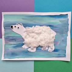 a polar bear made out of paper on top of a piece of blue and green paper