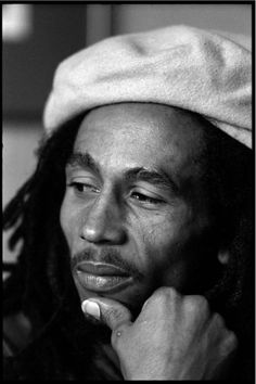 a black and white photo of a man with dreadlocks looking at the camera