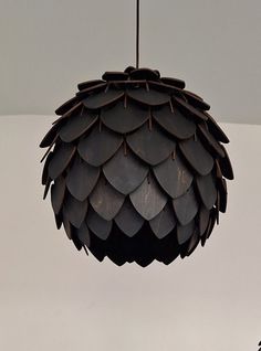 a light fixture hanging from the ceiling made out of metal leaves and wood strips, with two birds perched on top of it