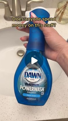 a hand holding a bottle of dawn dishwasher deterant in front of a sink