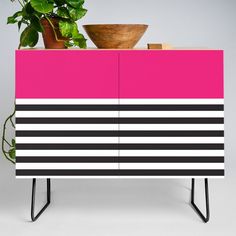 a potted plant sitting on top of a pink and black striped cabinet with metal legs