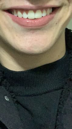 a close up of a person with a toothbrush in his mouth and wearing a black sweater