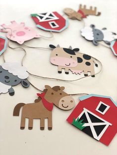 paper farm animals and barnyards hanging from strings on a white table cloth covered surface