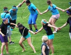 a group of people holding hands and playing tug - ball in the grass with each other