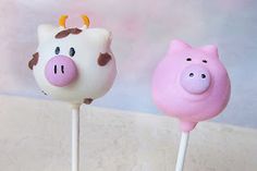 two marshmallows with pigs on them sitting next to each other in front of a wall