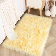 a fluffy yellow rug is on the floor next to a white bed and night stand