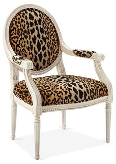 a leopard print upholstered chair with white frame and arms, on an isolated background