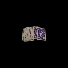 four purple and white playing cards against a black background