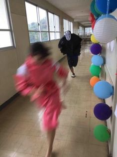 two women in kimonos walking down a hallway with balloons and streamers hanging from the ceiling