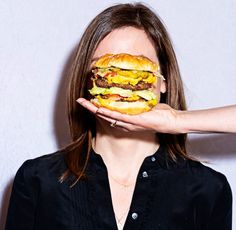 a woman holding up a hamburger in front of her face