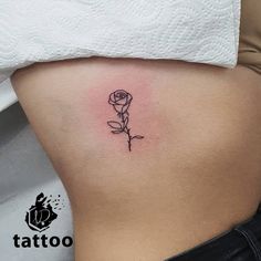 a small rose tattoo on the side of a woman's rib - up stomach