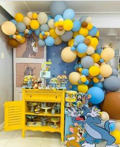 a room filled with lots of balloons and decorations on the wall, including a yellow table