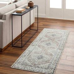 a living room with a couch, coffee table and rug on the hardwood flooring