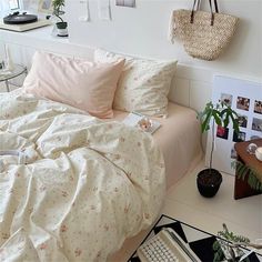 a bed with white sheets and pink comforter next to a wall with pictures on it