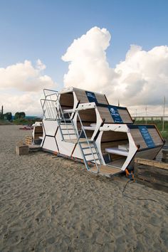 a large boat sitting on top of a sandy beach next to the ocean with ladders