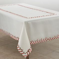 a white table cloth with red and grey designs on it, sitting on a tile floor