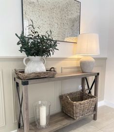 a table with two baskets and a vase on it next to a wall mounted mirror