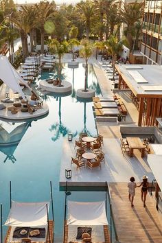 an aerial view of a resort pool with lounge chairs and umbrellas in the foreground