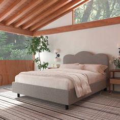 a large bed sitting in a bedroom on top of a wooden floor next to a window