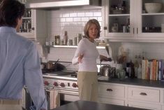 a woman standing in a kitchen next to a stove top oven