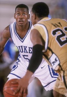 two young men playing basketball against each other on a court with one holding the ball