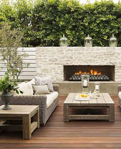 an outdoor living area with couches, tables and a fire place in the background