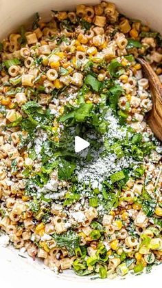 a pot filled with pasta and vegetables covered in parmesan cheese next to a wooden spoon