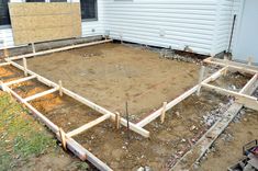 the foundation for a house being built in front of a building with siding on it