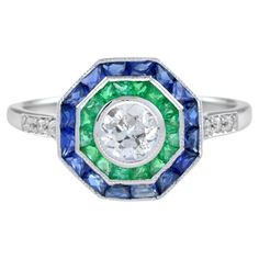 An incredibly stylish Art Deco target ring, set with a double halo clusters of gemstones – blue sapphire and emerald around a central old cut diamond. The diamonds are bright, displaying excellent flash and sparkle, while the sapphire and emerald have a great vivid color. Ring Information Style: Art-deco Metal: 18K White Gold Total weight: 2.93 g. (approx. total weight) Size: US7 (resizable) Center Gemstone Type: Diamond Shape: Old Cut Round Shape Average Color: H Average Clarity: SI Size: 4.5 m Blue Multi-stone Sapphire Ring In Art Deco Style, Blue Emerald Rings With Halo Setting, Blue Emerald Ring With Halo Setting, Blue Emerald Halo Setting Ring, Antique Emerald Engagement Ring, Target Ring, Double Halo Ring, Emerald Ring Engagement Diamond, Vintage Engagement Rings Sapphire