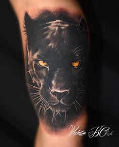 a black panther tattoo on the arm with yellow eyes and an orange - colored eye