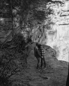 a man standing on top of a cliff next to a waterfall