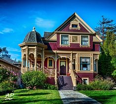 an old victorian style house with red and yellow trim on the front porch, stairs leading up to the second floor