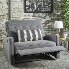 a gray and black couch sitting in front of a brick wall