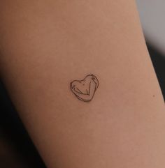 a small heart tattoo on the back of a woman's arm, with a black outline