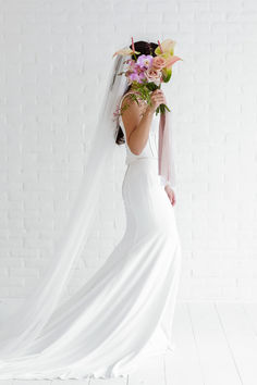 A Bride Holding A Bridal Bouquet With A White Background and A White Dress.