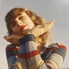 a woman holding her hand up to her face while standing in front of the sky