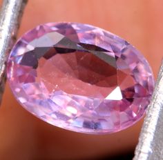 an oval shaped pink diamond sitting on top of a piece of metal