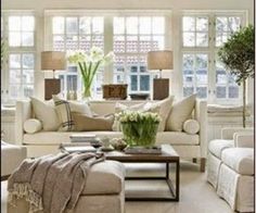 a living room filled with white furniture and lots of windows in it's walls