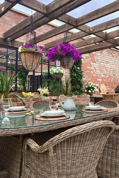 Traditional, elegant rattan dining set dressed with rattan placemats, bowls and wine glasses. Bright flower baskets hang from an overhead pergola. Cottagecore Patio, Cottagecore Garden, Inspiring Outdoor Spaces, Outdoor Dining Spaces, Timeless Furniture, Garden Seating, Small Garden Design