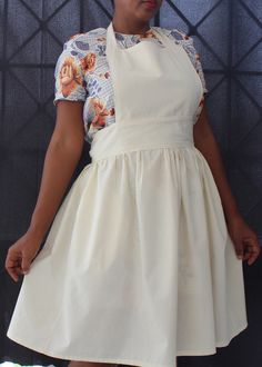 a woman standing in front of a wall wearing a white dress with flowers on it